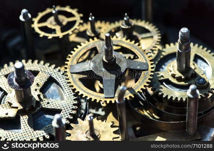 Close up metal gears mechanism. Golden colours. Hard light. Clock interior mechanism parts.