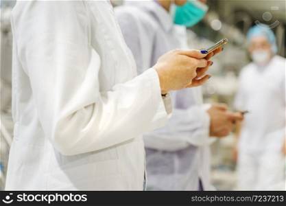 Close up midsection on unknown caucasian woman doctor holding smartphone at hospital - Medical workers group of surgeons using mobile phones at hospital in operating room - technology medicine concept