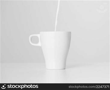 close up milk pouring into ceramic cup