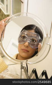 Close up mirror reflection of Asian/Indian young woman wearing eye mask.