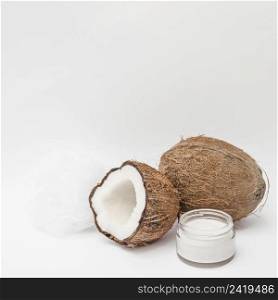 close up moisturizing cream loofah coconut white backdrop