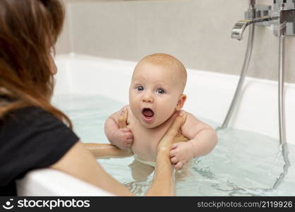 close up mother washing baby bathtub