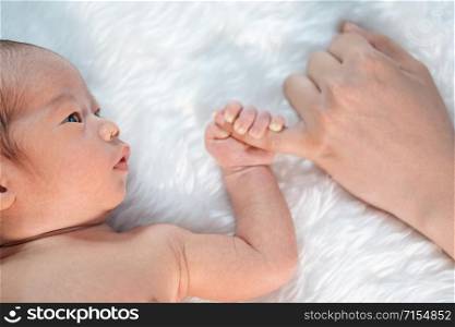 close up newborn baby boy holding little finger of mother&rsquo;s hand