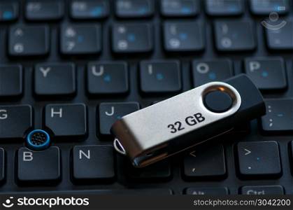 Close-up of a 32 GB pen drive. Keyboard in background.