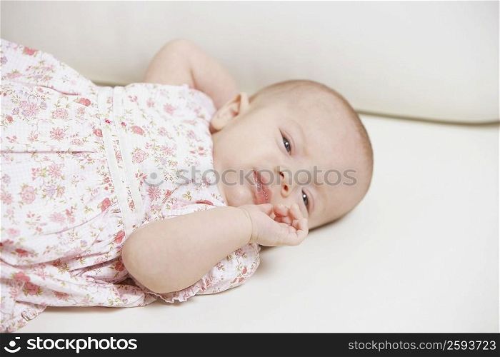Close-up of a baby girl lying on the bed