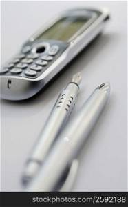 Close-up of a ballpoint pen and a fountain pen with a mobile phone