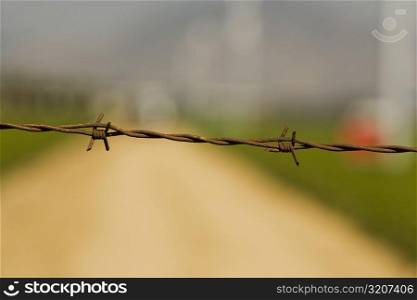 Close-up of a barbed wire fence on a farm