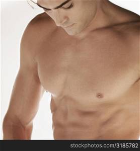 Close-up of a bare chested young man looking down