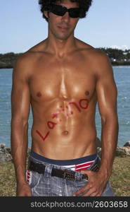 Close-up of a bare chested young man with Latino written on his chest