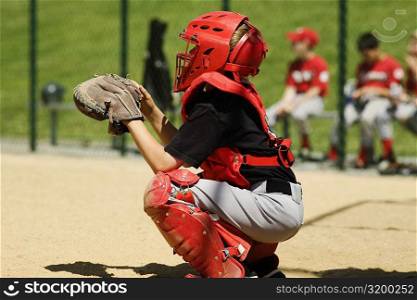 Close-up of a baseball catcher crouching on a baseball field