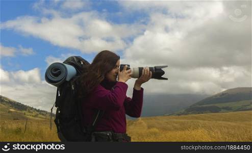 Close up of a beautiful Hispanic female scout with a backpack taking a photo with a telephoto lens on a morning. Close up of a beautiful Hispanic female scout with a backpack taking a photo with a telephoto lens
