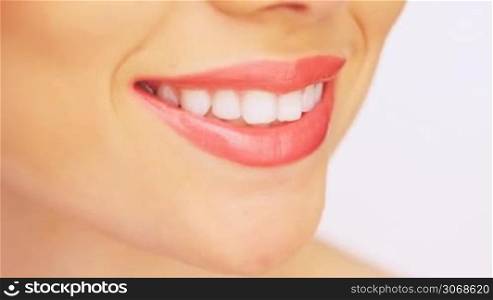 Close up of a beautiful toothy female smile with soft red lipstick on her lips and clean white teeth
