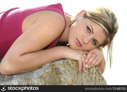 Close up of a beautiful young woman resting outside on a rock.