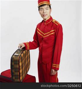 Close-up of a bellhop standing and holding a suit case