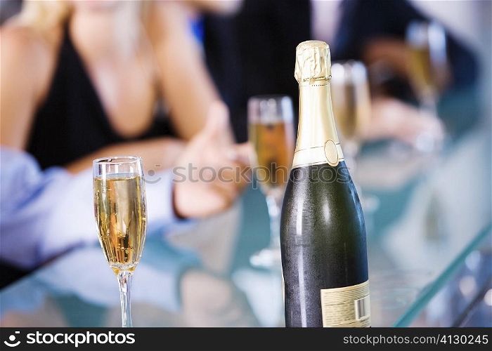 Close-up of a bottle of champagne and champagne flutes on a bar counter