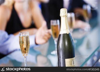 Close-up of a bottle of champagne and champagne flutes on a bar counter