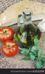Close-up of a bottle of olive oil and two tomatoes