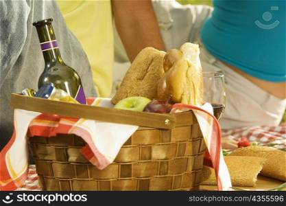 Close-up of a bottle with fruit and buns in a basket