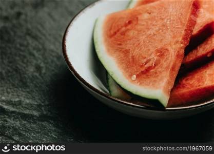 Close up of a bowl filled with watermelon over a black marble table, fresh food, wellness, healthy food