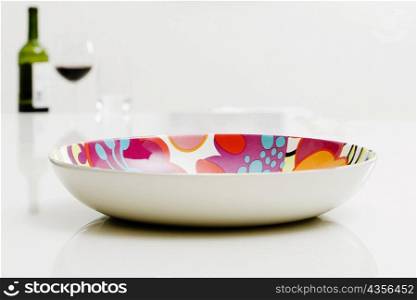 Close-up of a bowl with a bottle of red wine in the background