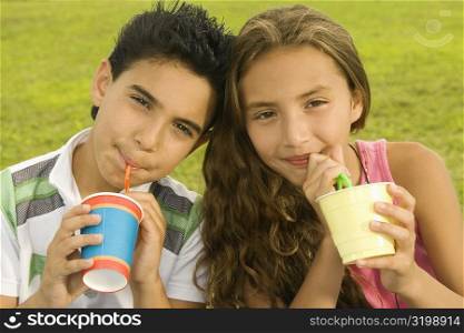 Close-up of a boy and a girl drinking with drinking straws