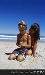 Close-up of a boy and girl sitting on the beach