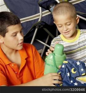 Close-up of a boy and his brother holding a water bottle