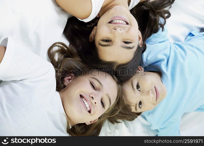 Close-up of a boy and his two sisters lying on the bed