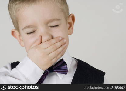 Close-up of a boy covering his mouth with his hands