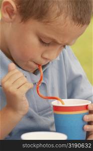 Close-up of a boy drinking from a cup with a straw