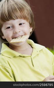 Close-up of a boy holding a biscuit in his mouth