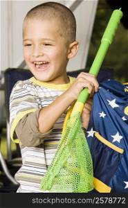 Close-up of a boy holding a butterfly net and a bag