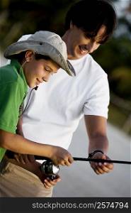 Close-up of a boy holding a fishing rod with his father