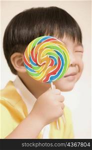 Close-up of a boy holding a lollipop over his face