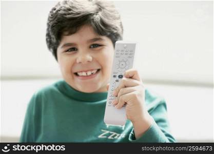 Close-up of a boy holding a remote control and smiling