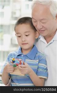 Close-up of a boy holding a toy with his grandfather