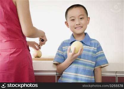 Close-up of a boy holding an apple with his mother beside him