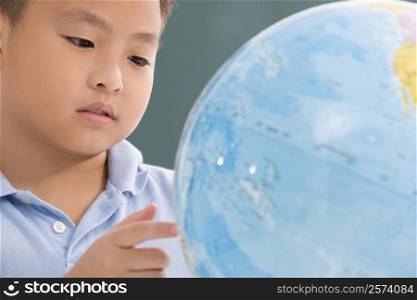 Close-up of a boy looking at a globe