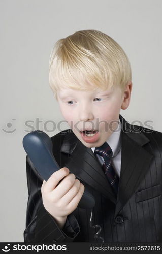 Close-up of a boy looking at a telephone receiver in shock