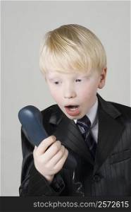 Close-up of a boy looking at a telephone receiver in shock