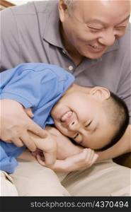 Close-up of a boy lying down in his grandfather lap and smiling