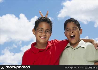 Close-up of a boy making a gesture of rabbit ears behind another boy&acute;s head