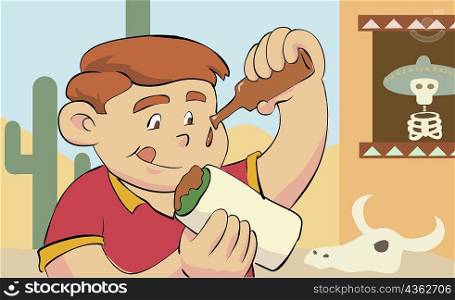 Close-up of a boy pouring tomato sauce on a sandwich