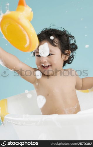 Close-up of a boy sitting in a bathtub and smiling