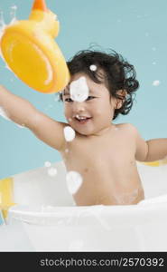 Close-up of a boy sitting in a bathtub and smiling