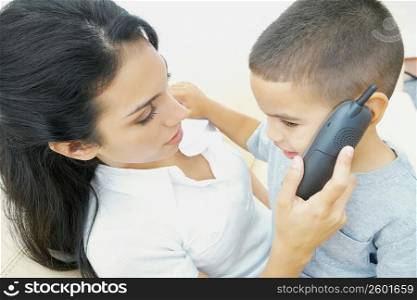Close-up of a boy sitting on his mother&acute;s lap and talking on a mobile phone