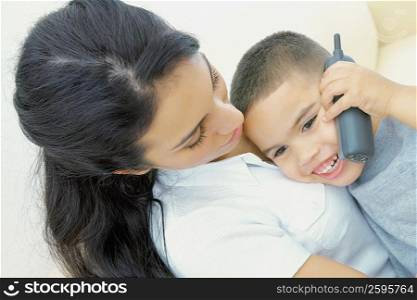 Close-up of a boy talking on a mobile phone with his mother beside him