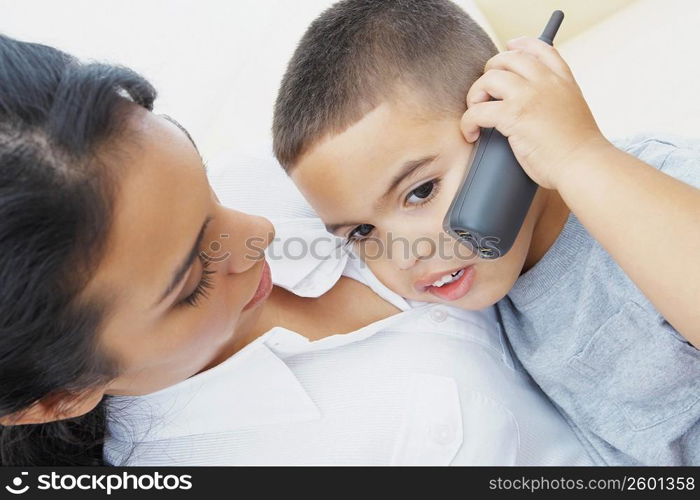 Close-up of a boy talking on a mobile phone with his mother beside him