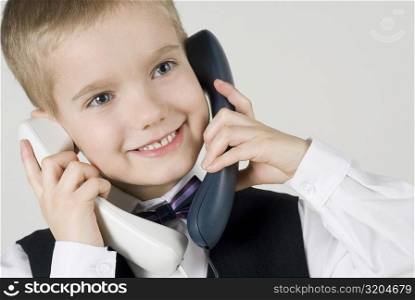 Close-up of a boy talking on two landline phones