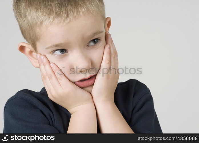 Close-up of a boy thinking with his head in his hands